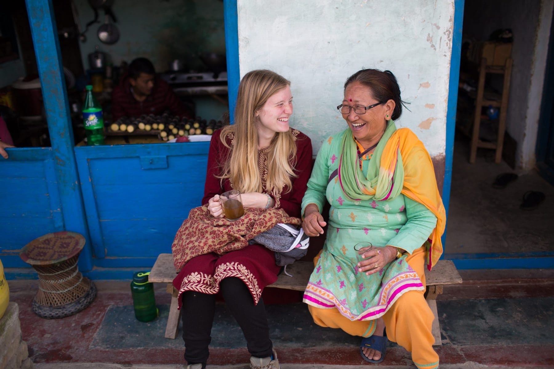 Missionary and her local friend dressed up in traditional clothes, having a cup of tea